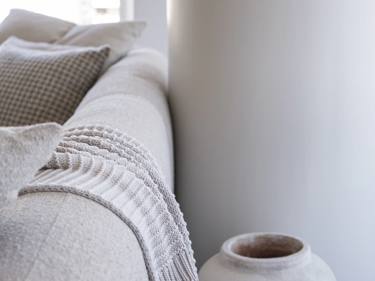 Elegant soft sofa and sculptural decorative vase in a neutral interior